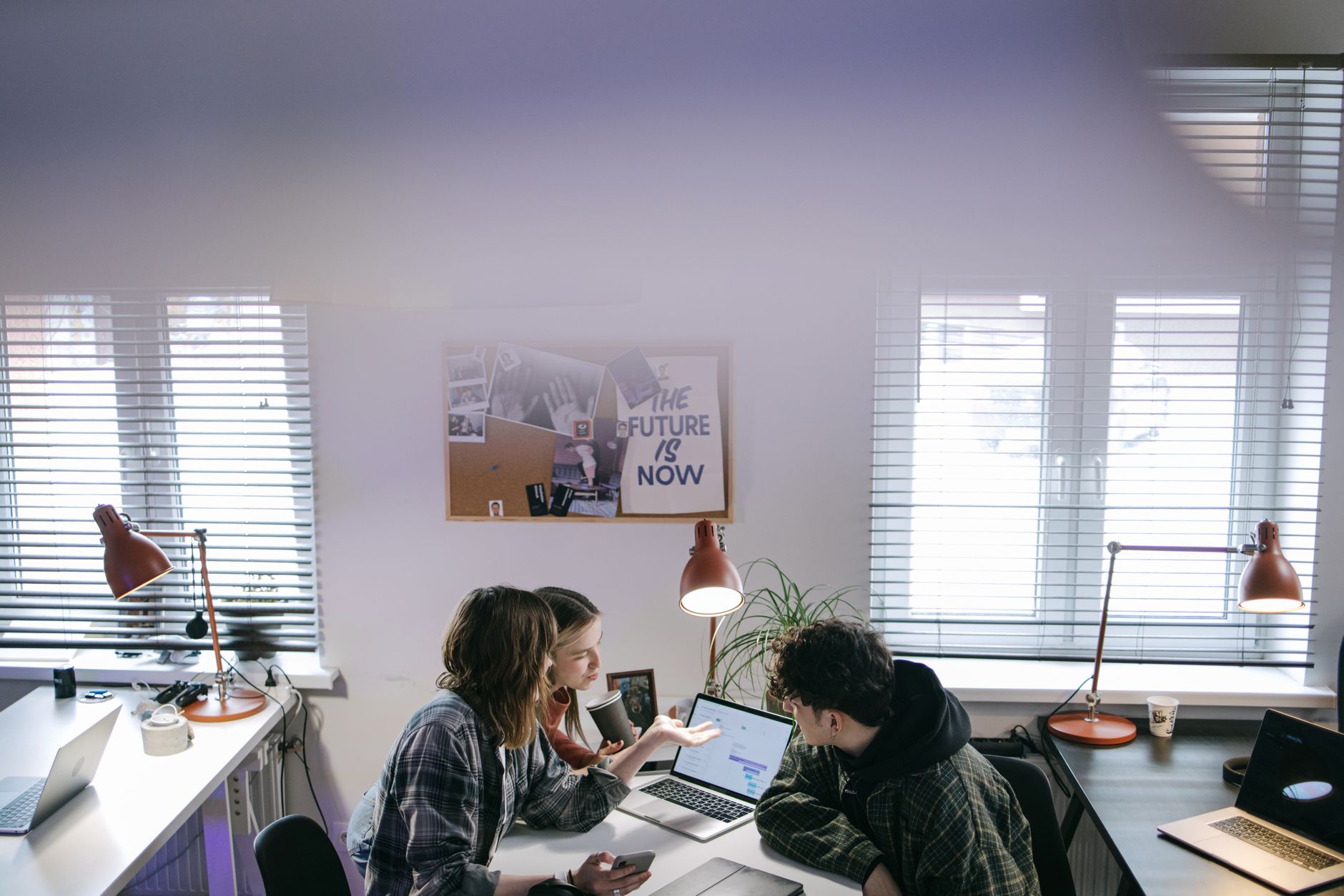 A group of people discussing ideas around laptops in a bright, modern office space — illustrating: How to Choose a US MSSP in Central Florida Without Overpaying for Features You Don't Need